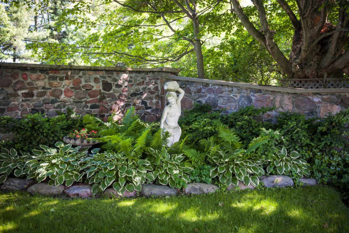 A beautiful backyard garden with perennial flowers and a statue.